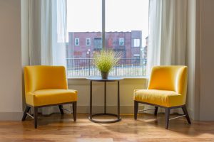Two empty yellow chairs across from each other in a therapists office.