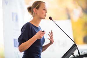 Young woman giving a presentation in a conference/meeting setting.
